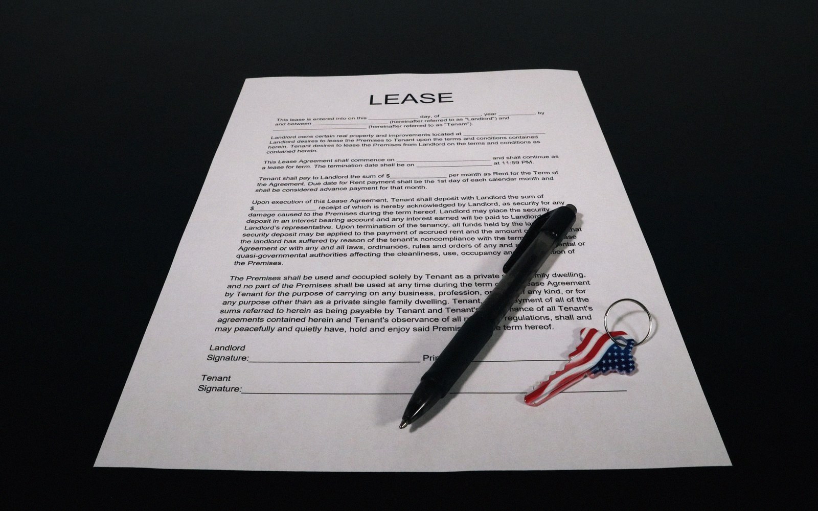 A lease agreement document with a pen and a house-shaped keychain resting on it