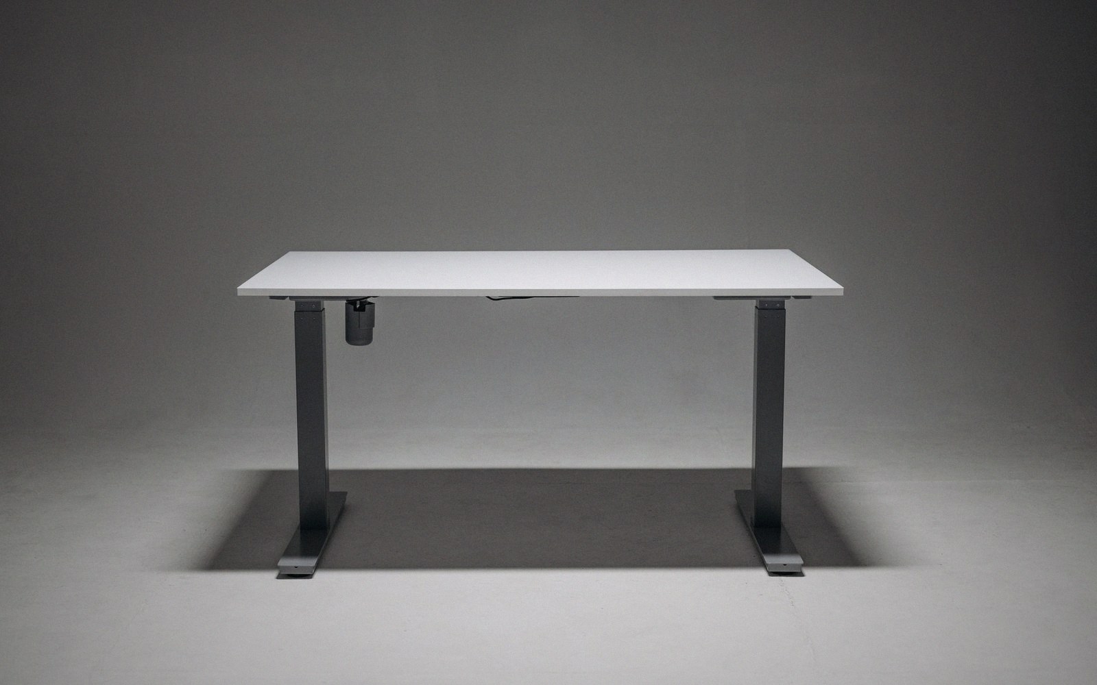 White electric standing desk with a motorized adjustable frame on gray legs