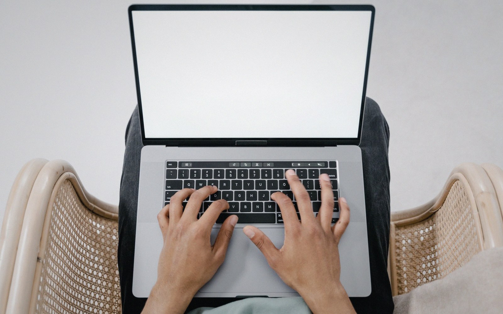 Overhead view of hands typing on a laptop with a blank white screen