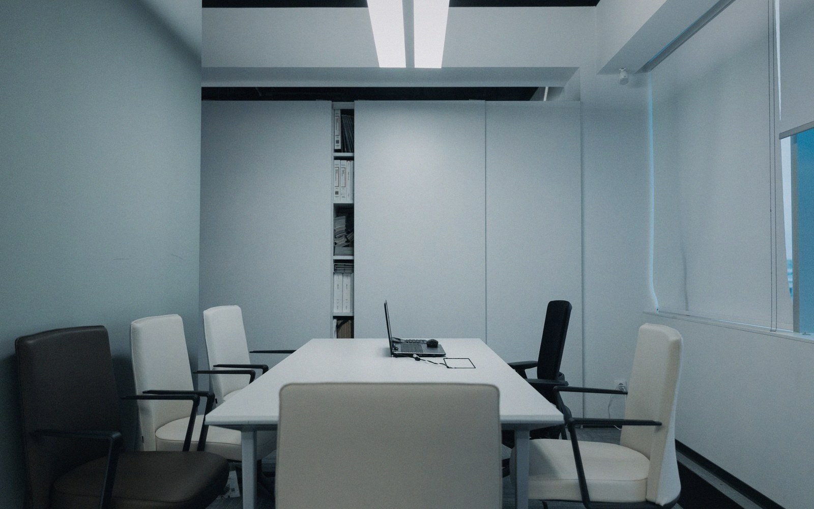 Empty conference room with a laptop on the table surrounded by office chairs