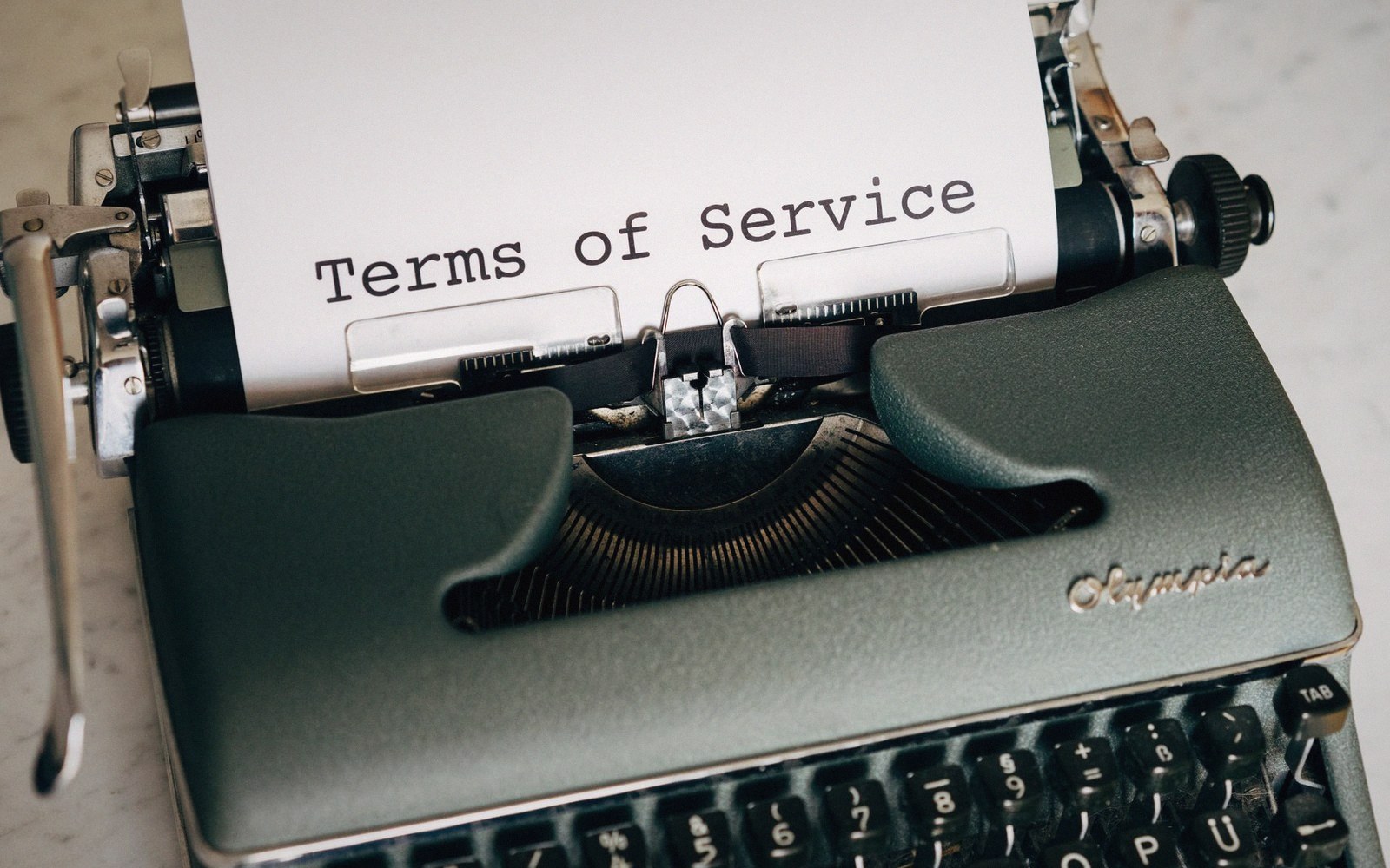 A vintage Olympia typewriter with a sheet reading "Terms of Service" rolled into it