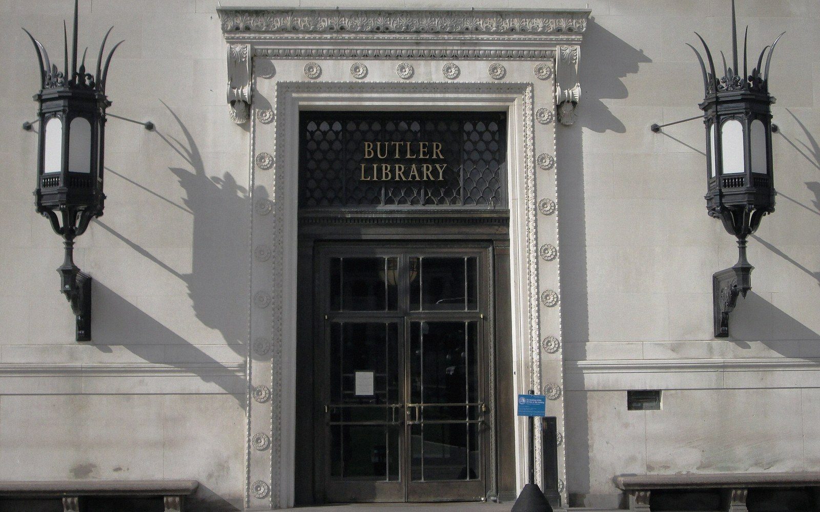 Ornate stone entrance of Butler Library flanked by two lantern-style wall sconces